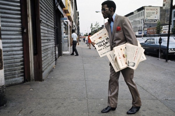 Harlem: The Ghetto. New York City- Harlem- juillet 1970: le ghetto; un afro-amÈricain trËs ÈlÈgant, costume et noeud papillon, vend ou distribue des journaux sur l'Islam et les musulmans dans une rue. (Photo by Jack Garofalo/Paris Match via Getty Images)