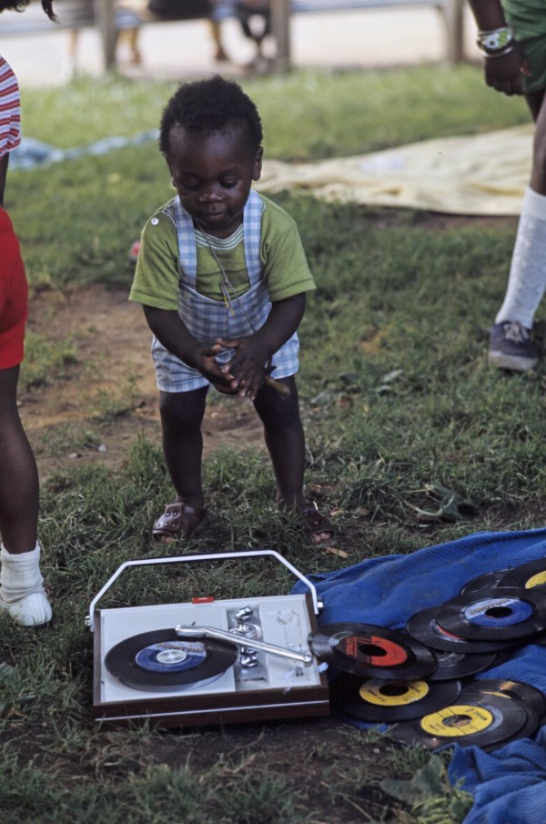 Harlem: The Ghetto. New York City- Harlem- juillet 1970: le ghetto; un jeune enfant afro-amÈricain bat le rythme avec ses mains devant un tourne-disque et des vinyles sur une pelouse. (Photo by Jack Garofalo/Paris Match via Getty Images)