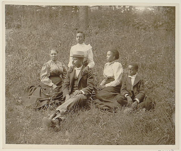 African American family posed for portrait seated on lawn