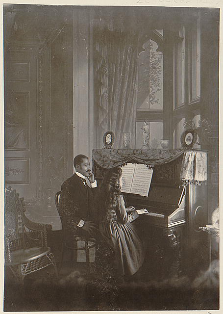 African American man giving piano lesson to young African American woman