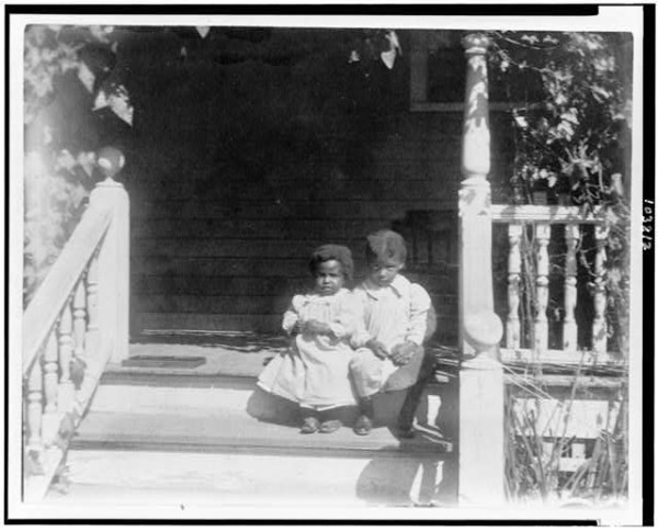 Two African American children sitting on steps to porch