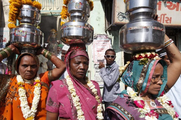 Sidi women carry sacred water on their heads through the town during their communities annual Urs celebration. Happening only once a year and lasting several days they give offerings to their Saint Bava Gor. Jamnagar, Gujarat, India